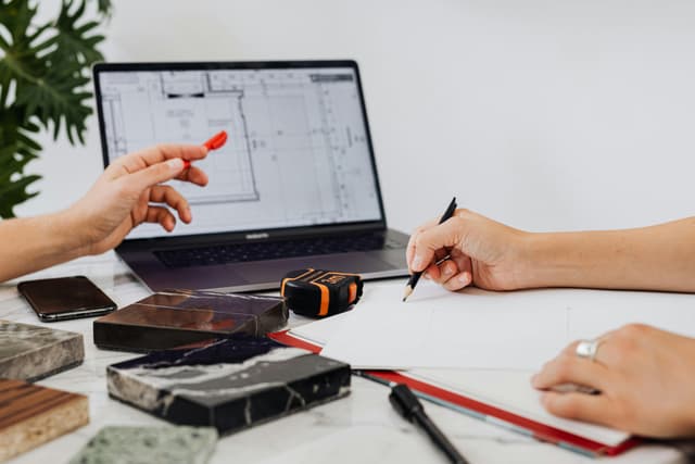 Person working on laptop with architectural plans